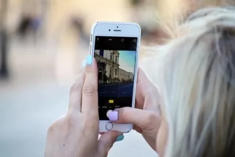 uma mulher loira tirando foto pelo celular